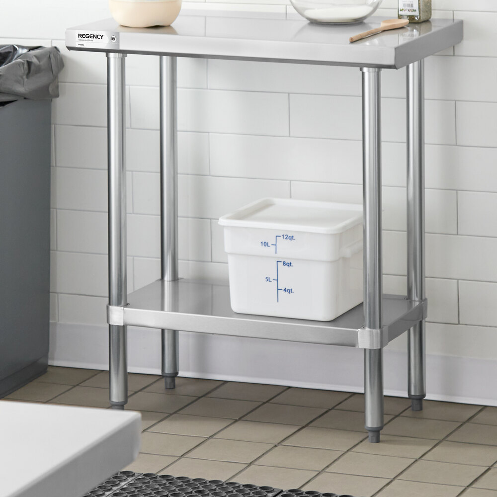 A stainless steel work table with an undershelf, holding a white plastic container with measurement markings.