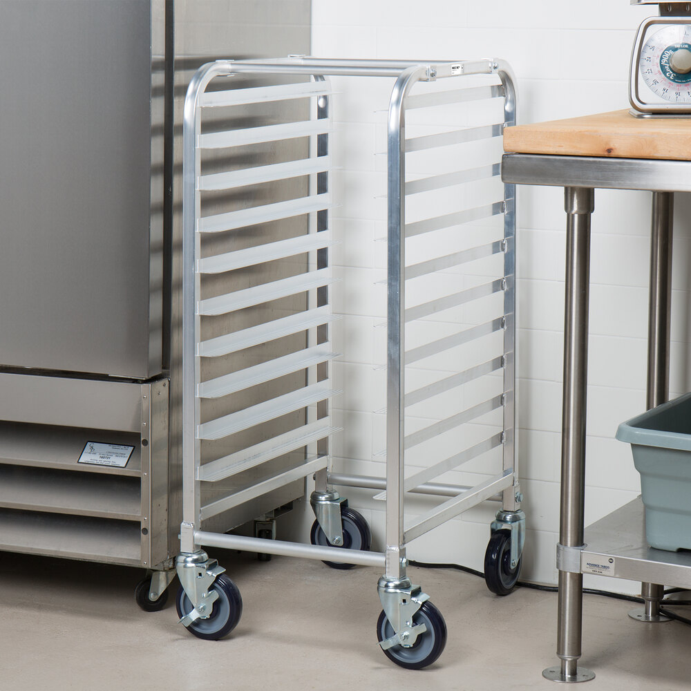 A metal rack with multiple horizontal slots and four caster wheels, positioned in a commercial kitchen setting.