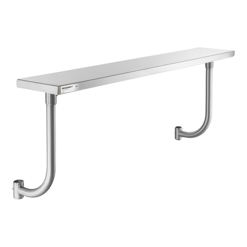 A long, rectangular stainless steel shelf with two curved metal supports attached to a wall.
