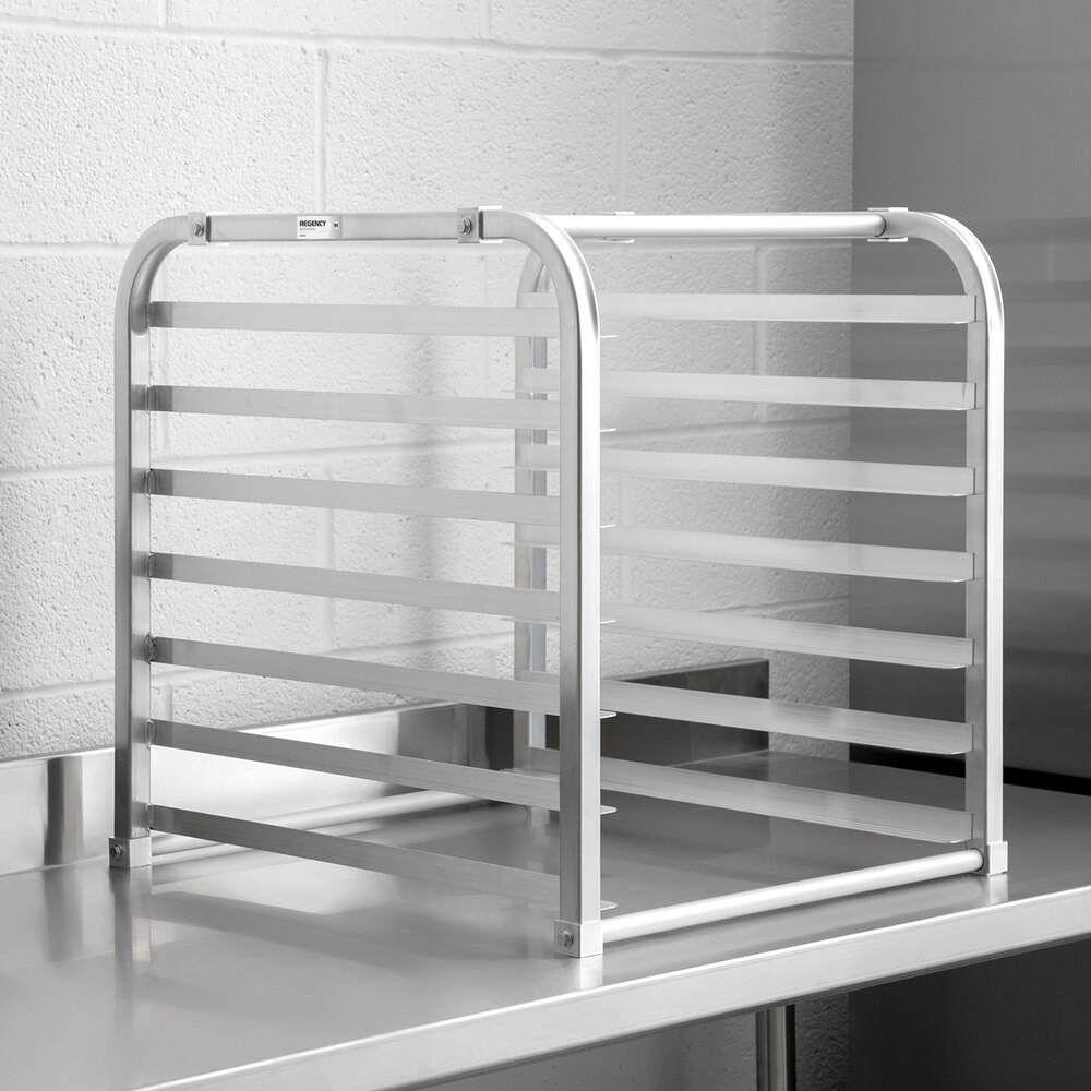 A metal rack with seven horizontal slots, designed to hold trays or pans, is placed on a stainless steel countertop.