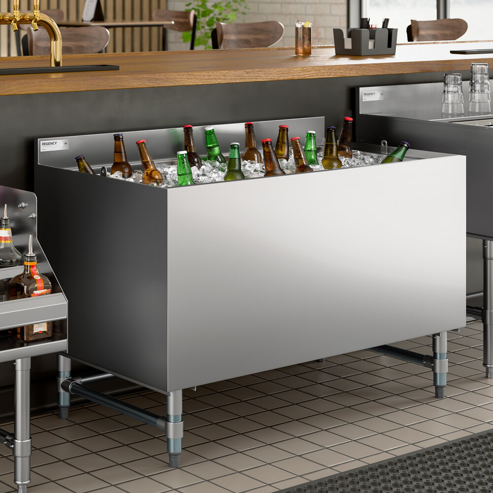 A stainless steel beer box with a backsplash, filled with ice and assorted bottled beverages, designed for bar or restaurant use.