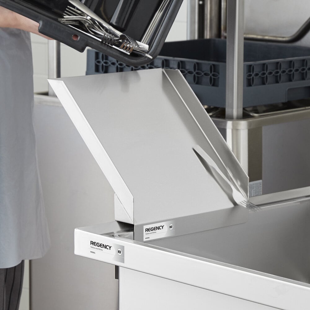 A metal chute attached to the side of a stainless steel sink, with utensils being emptied from a tray above.