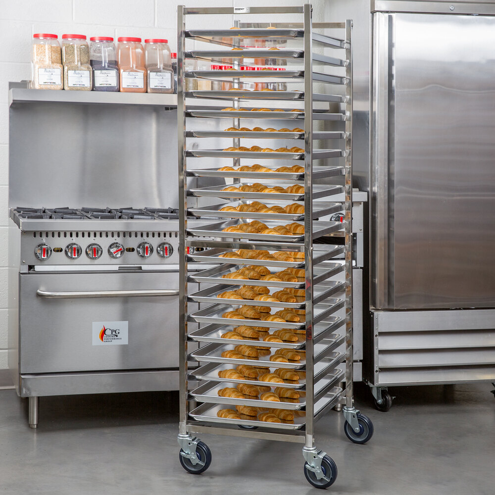 A tall, stainless steel rack on wheels holds multiple trays of baked goods in a commercial kitchen setting.