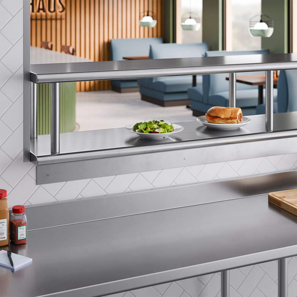 A stainless steel pass-through shelf with an overshelf installed in a commercial kitchen setting.