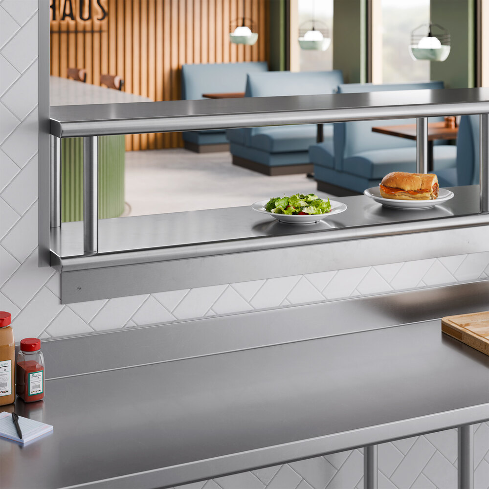 A stainless steel pass-through shelf with an overshelf installed in a commercial kitchen setting.