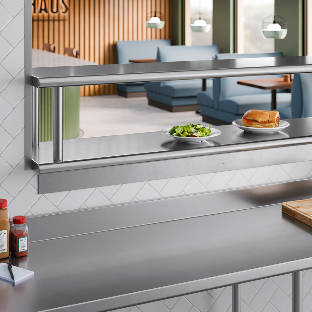 A stainless steel pass-through shelf with an overshelf installed in a commercial kitchen setting.