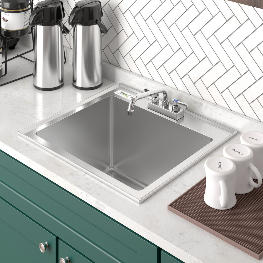 A Regency stainless steel drop-in sink with a white coffee mug and containers on the counter above.
