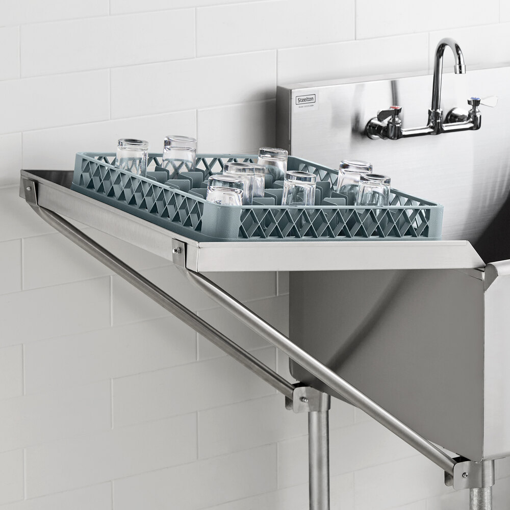 A stainless steel drainboard attached to a sink, holding a rack of glassware.