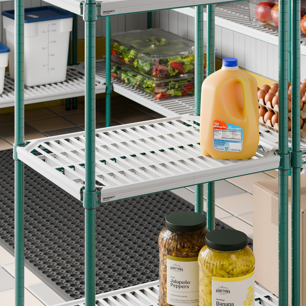 A green metal shelving unit with white slatted shelves, holding various food items including a jug of orange liquid, jars, and containers.