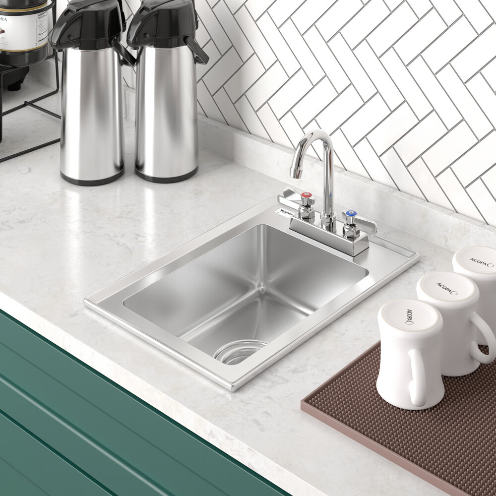A stainless steel single-basin sink with a faucet is installed in a white countertop, surrounded by coffee dispensers and mugs.