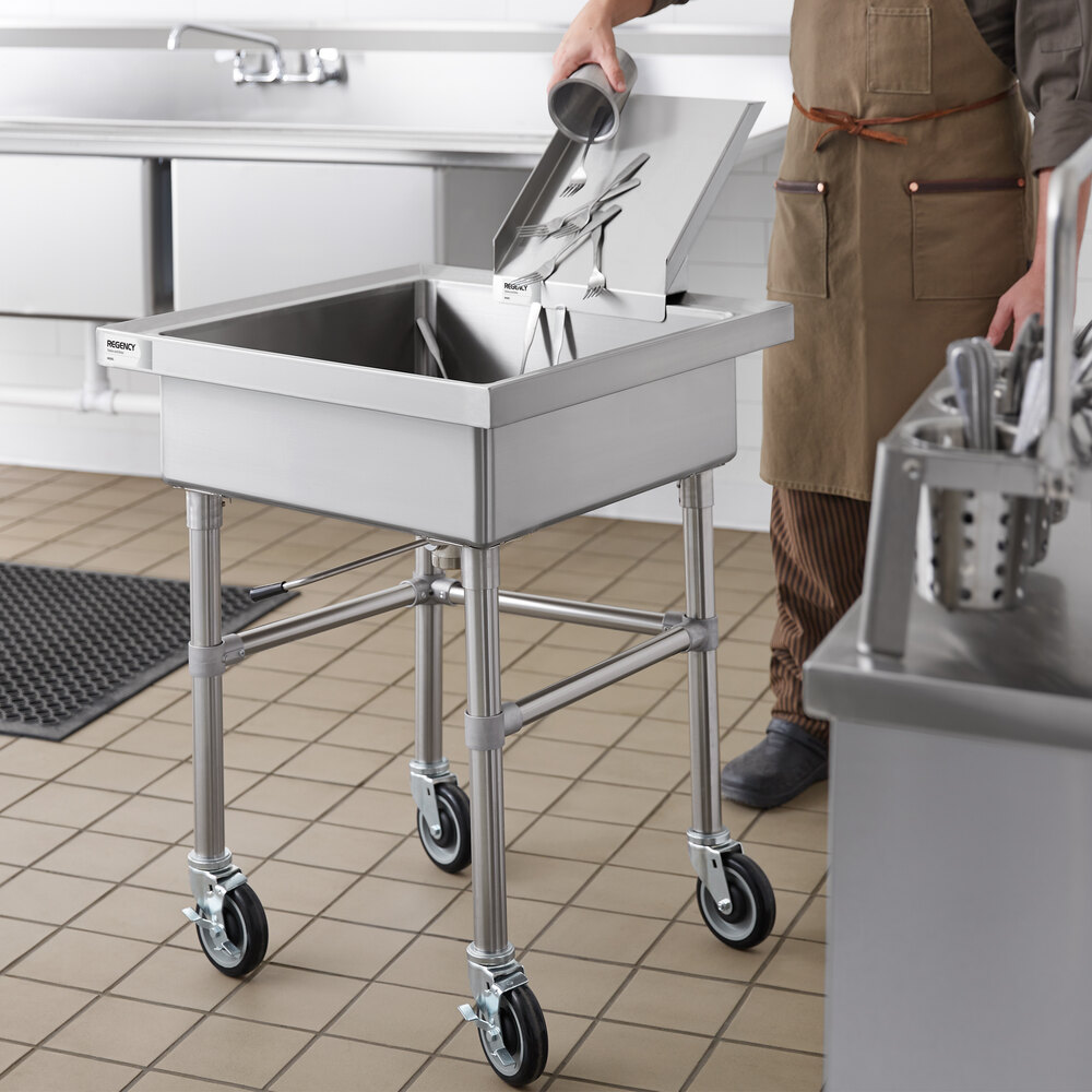 A stainless steel mobile soaking sink with a detachable chute, shown in a commercial kitchen setting with utensils being placed inside.