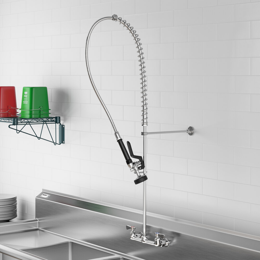 A commercial-style wall-mounted pre-rinse faucet with a long flexible hose and spray nozzle installed above a stainless steel sink.