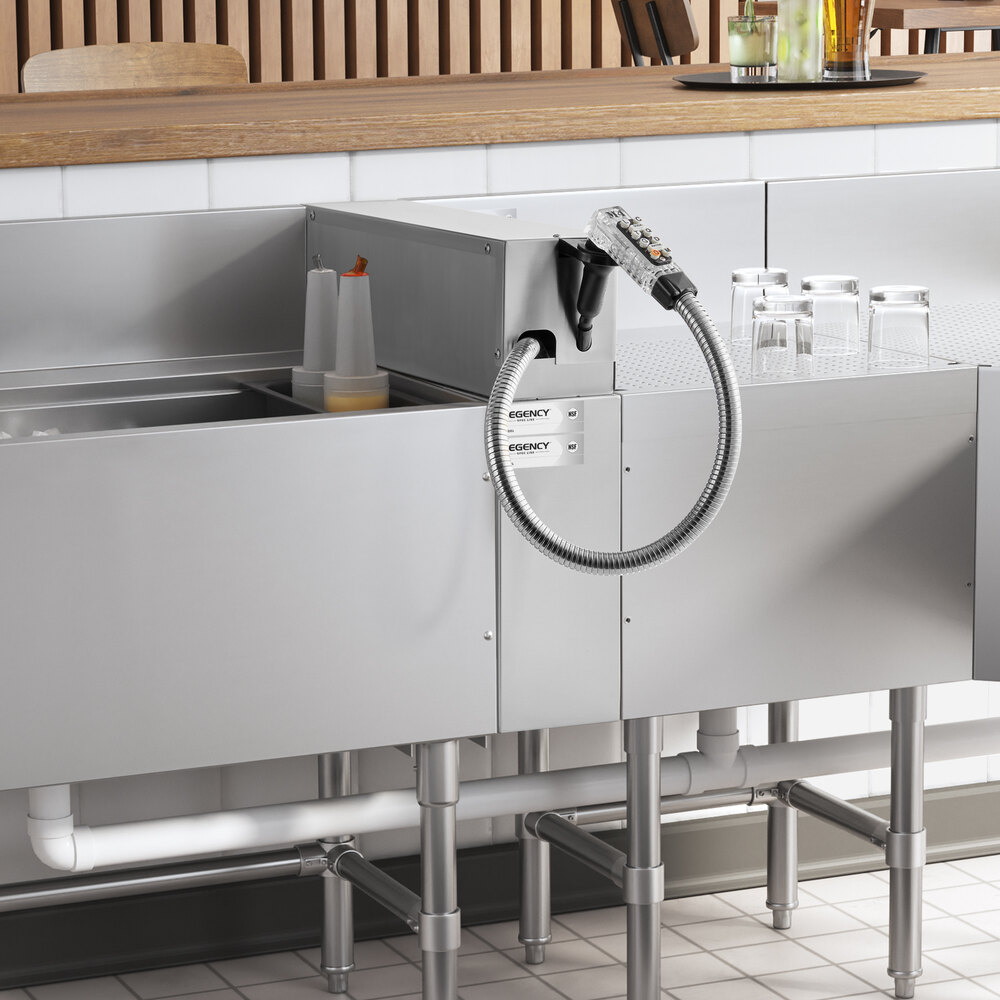 A stainless steel countertop with an attached flexible soda gun holder, some condiment bottles, and several upside-down glasses.