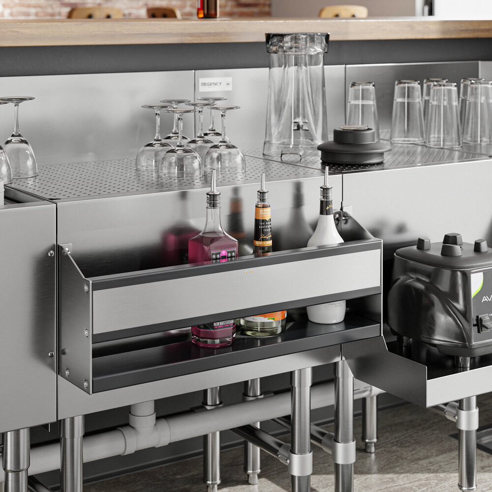 A Regency stainless steel speed rail on a kitchen counter with a shelf full of bottles.