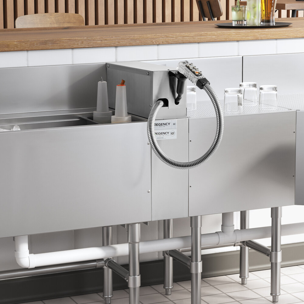 A Regency stainless steel soda gun holder on a counter above a sink with a faucet and a hose.