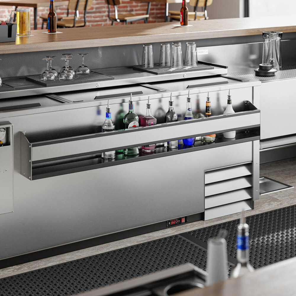 A stainless steel Regency speed rail on a counter in a cocktail bar with bottles and glasses.