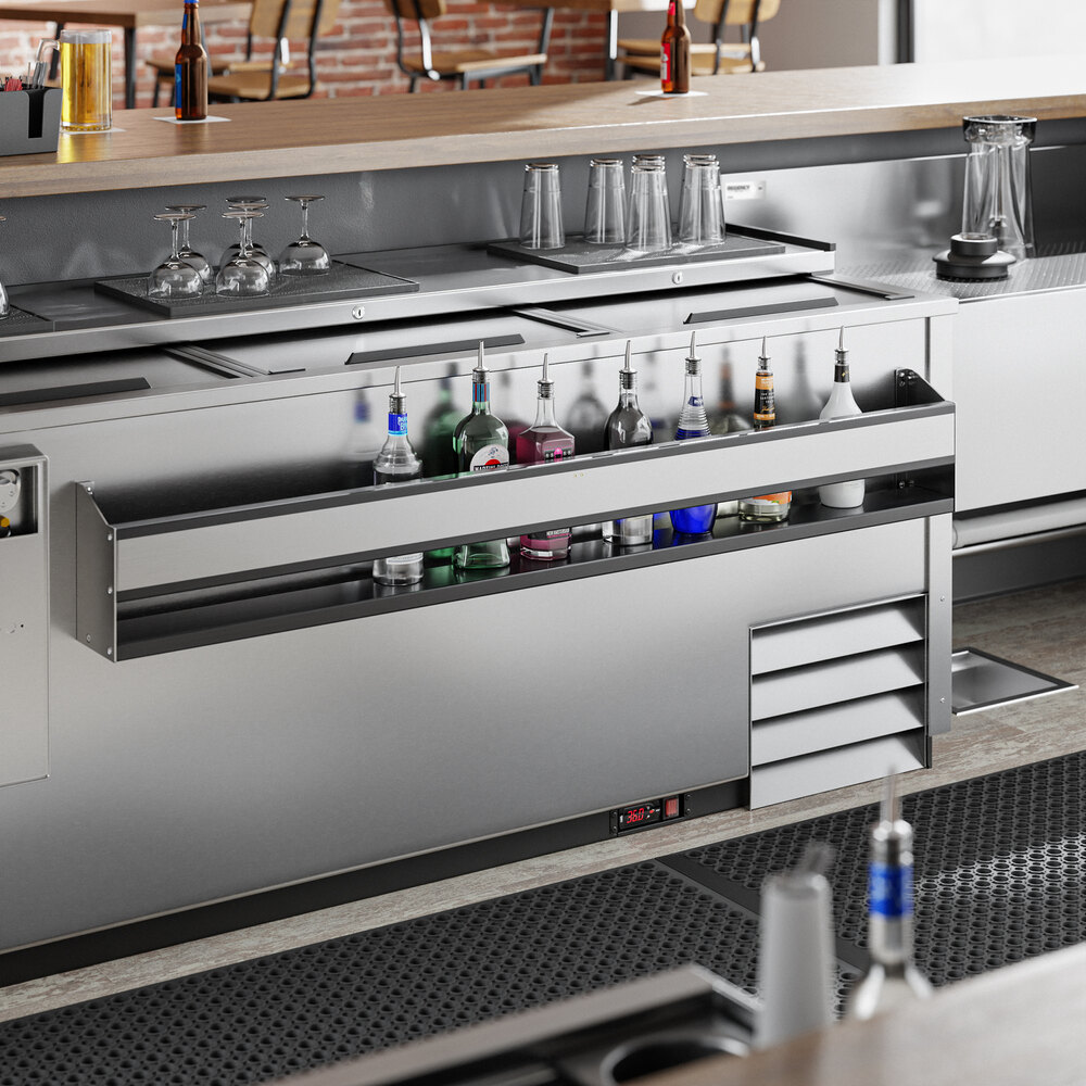 A stainless steel bar setup with a single tier speed rail holding various liquor bottles and glassware above.