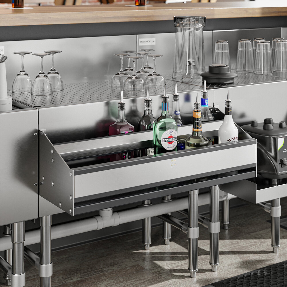 A Regency stainless steel speed rail on a bar counter with bottles.
