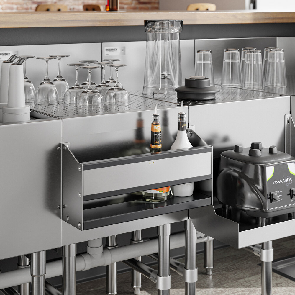 A stainless steel bar setup with glassware, bottles, a blender, and an 18-inch single tier speed rail mounted below the counter.