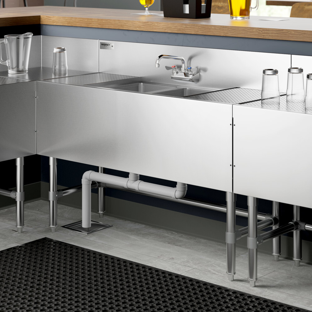 A Regency stainless steel underbar sink with (2) drainboards and a faucet on a counter.