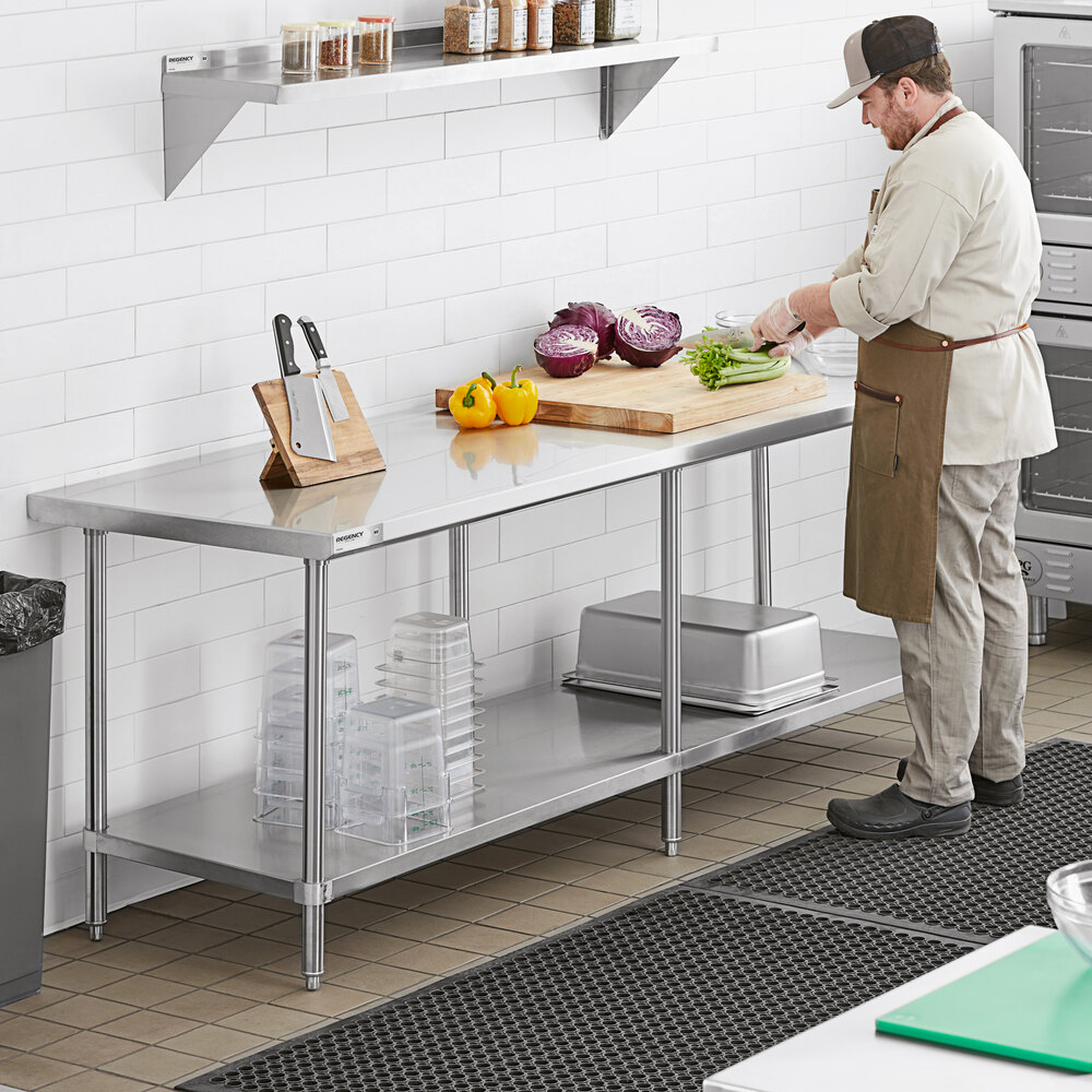 A person is preparing food on a stainless steel work table with a lower shelf, cutting vegetables on a wooden board, with kitchen utensils and containers visible nearby.