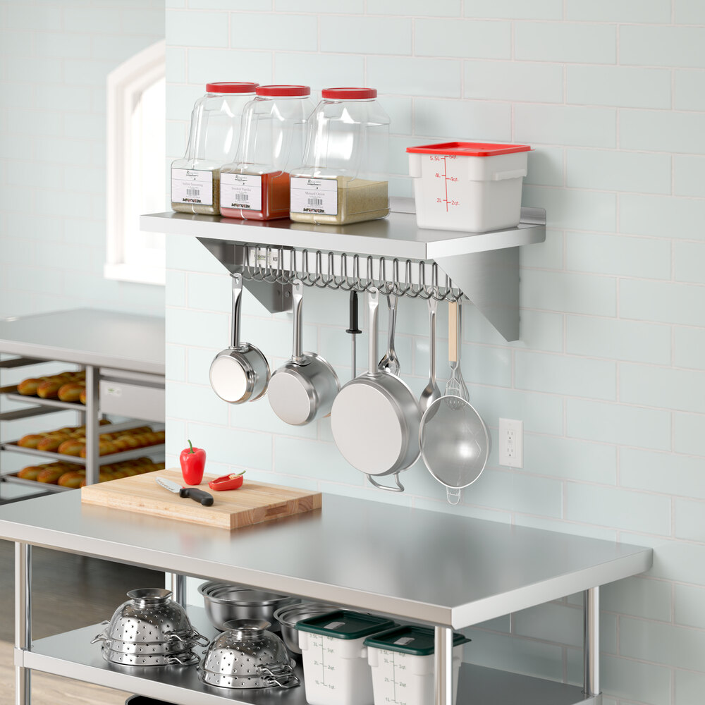 A kitchen with a Regency stainless steel wall-mounted pot rack shelf holding pots and pans.