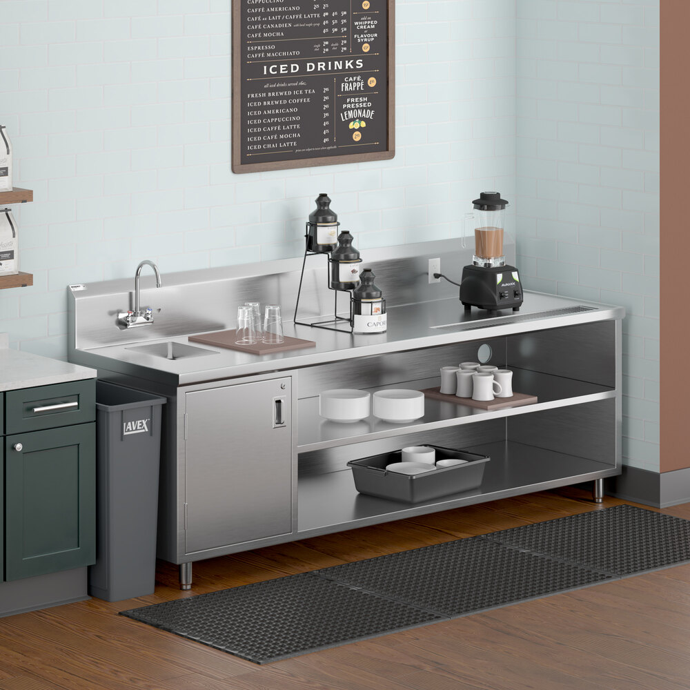 A stainless steel beverage station with a left-side sink, gooseneck faucet, open shelves, and various drink preparation items on top.