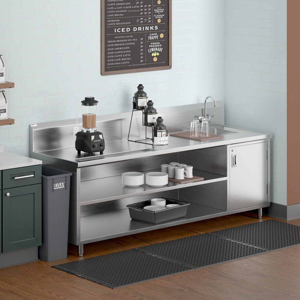 A stainless steel beverage station with open shelves, a blender, beverage dispensers, a right-side sink with a gooseneck faucet, and various cups and containers.