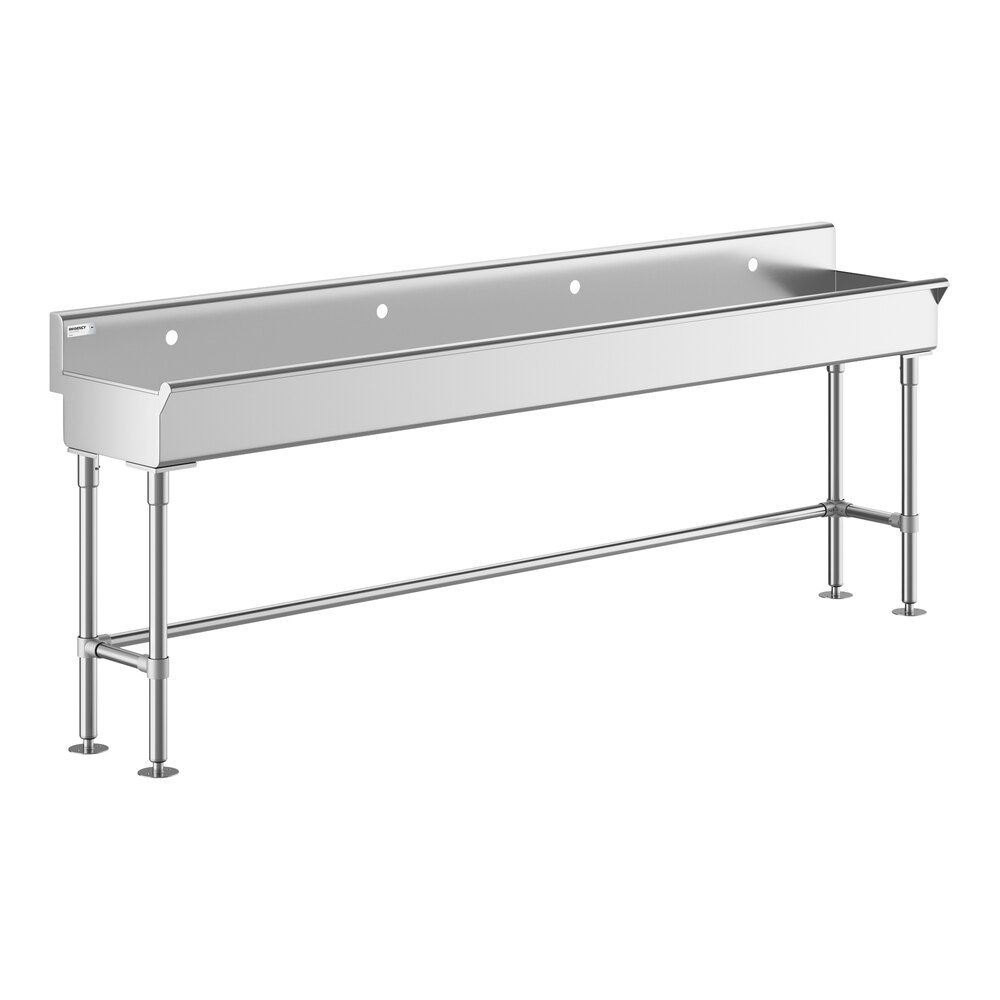 A long, stainless steel hand sink with four legs and a backsplash featuring four faucet holes.