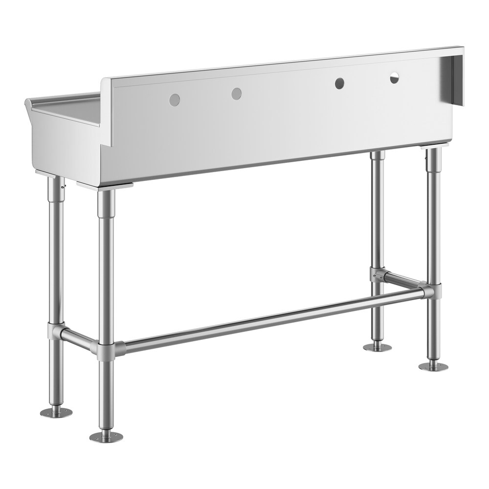 A stainless steel hand sink with four legs, a rectangular basin, and multiple faucet holes on the back panel.
