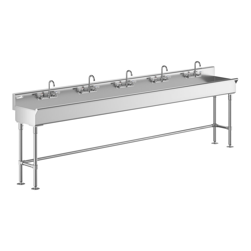 A long stainless steel hand sink with five faucets evenly spaced along its length, supported by metal legs.