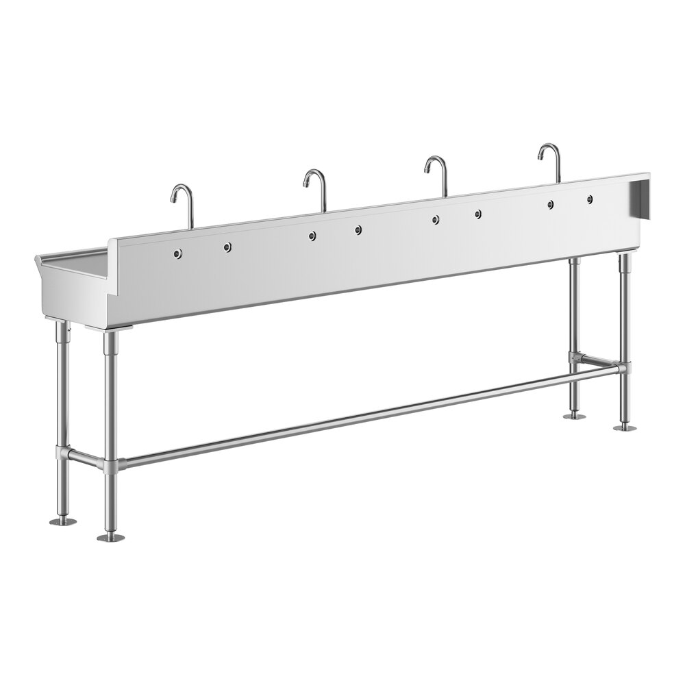 A long, stainless steel hand sink with four faucets evenly spaced along the back edge, supported by metal legs.
