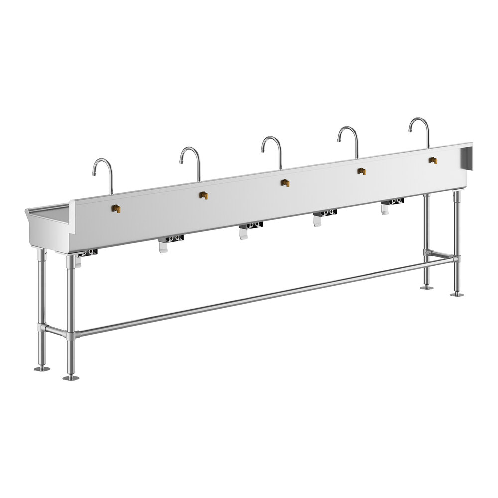 A long, stainless steel hand sink with five gooseneck faucets and knee-operated controls, supported by metal legs.