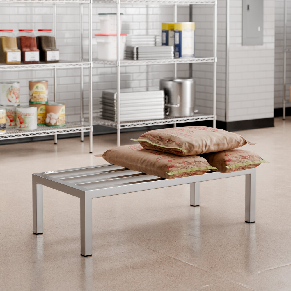 A metal rack with a slatted top holding several large brown bags, situated in a commercial kitchen or storage area.
