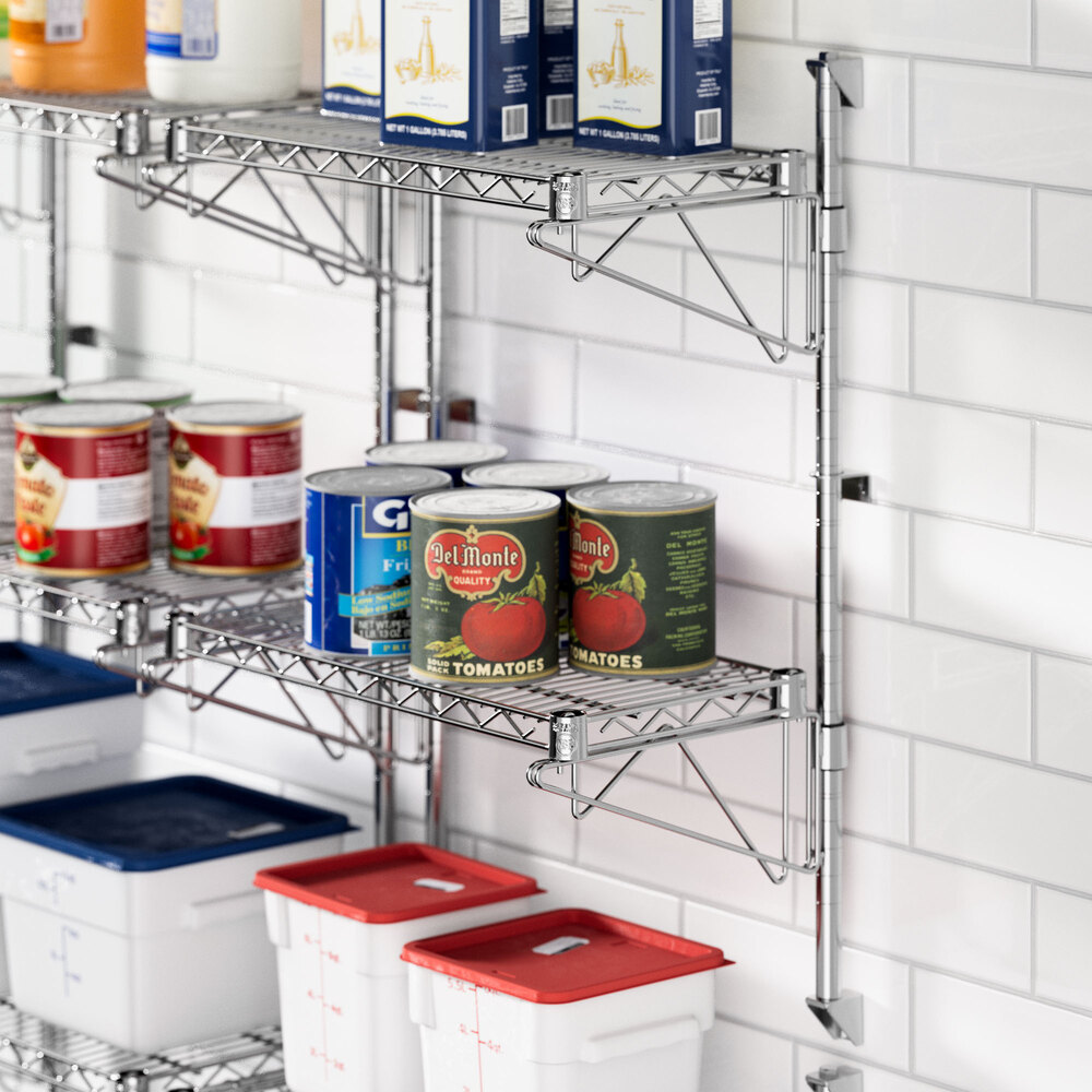 A metal Regency wall-mount wire shelf with cans of food on it.