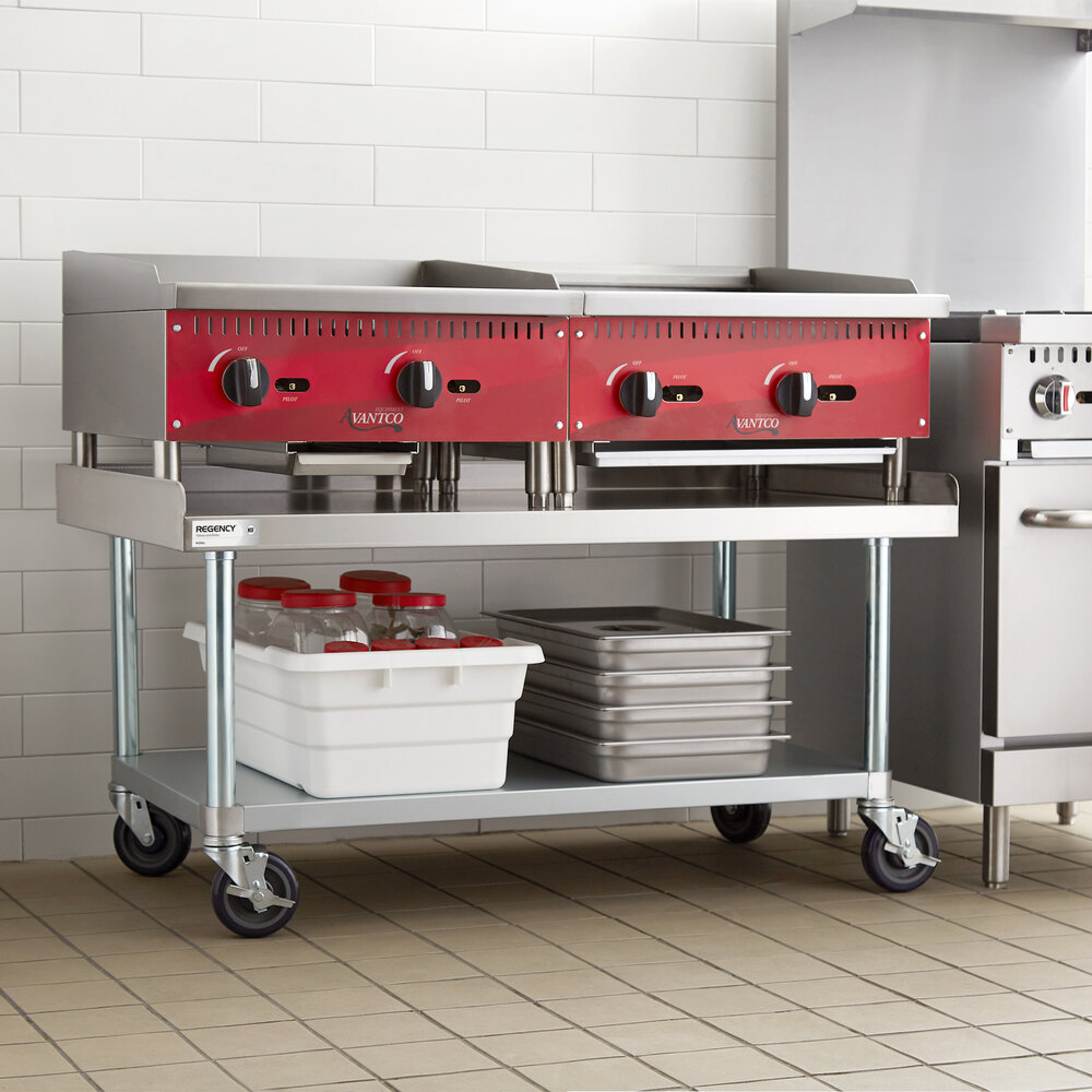 A stainless steel equipment stand with a lower galvanized shelf and casters, holding kitchen appliances and storage containers.