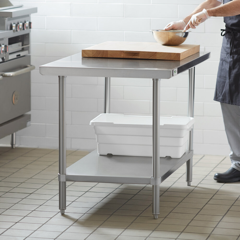 A stainless steel work table with an adjustable undershelf, shown with a cutting board and storage bins.