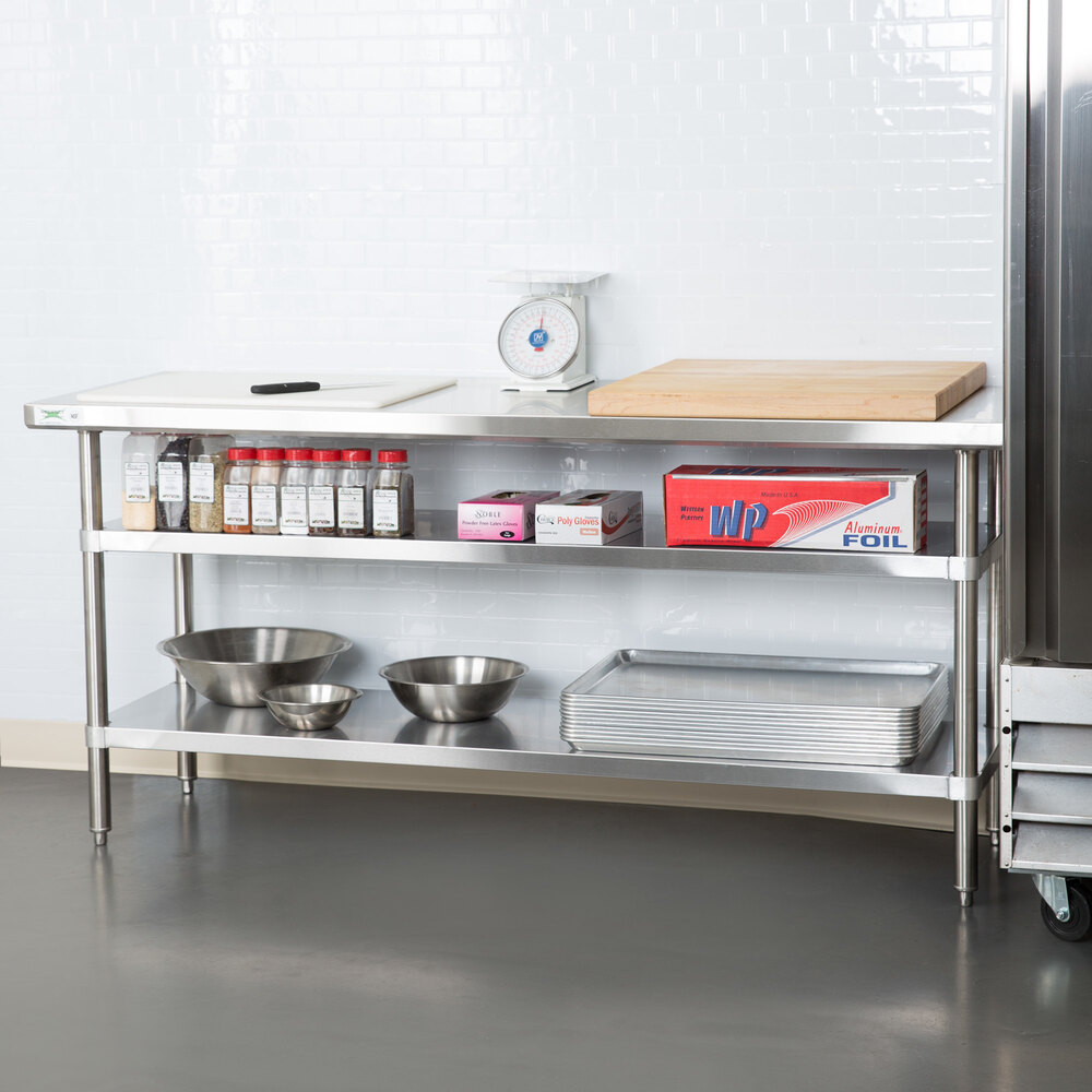 A stainless steel adjustable undershelf installed on a commercial kitchen work table.