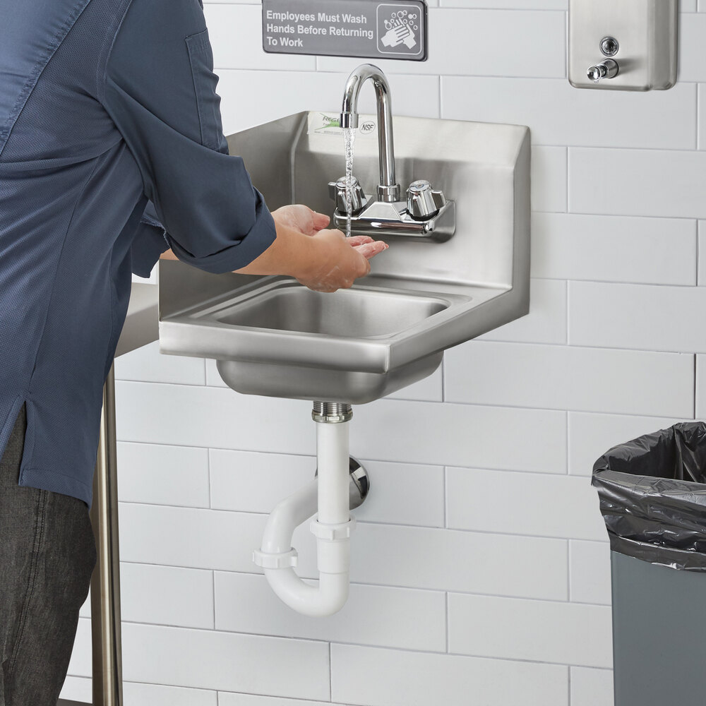 A person washing their hands in a Regency wall-mounted hand sink.