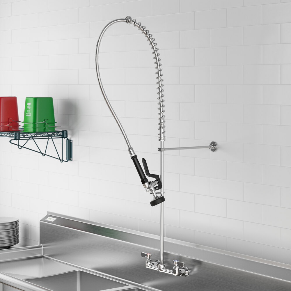 A wall-mounted pre-rinse faucet with an 8-inch center and a flexible spray hose, installed above a commercial kitchen sink.