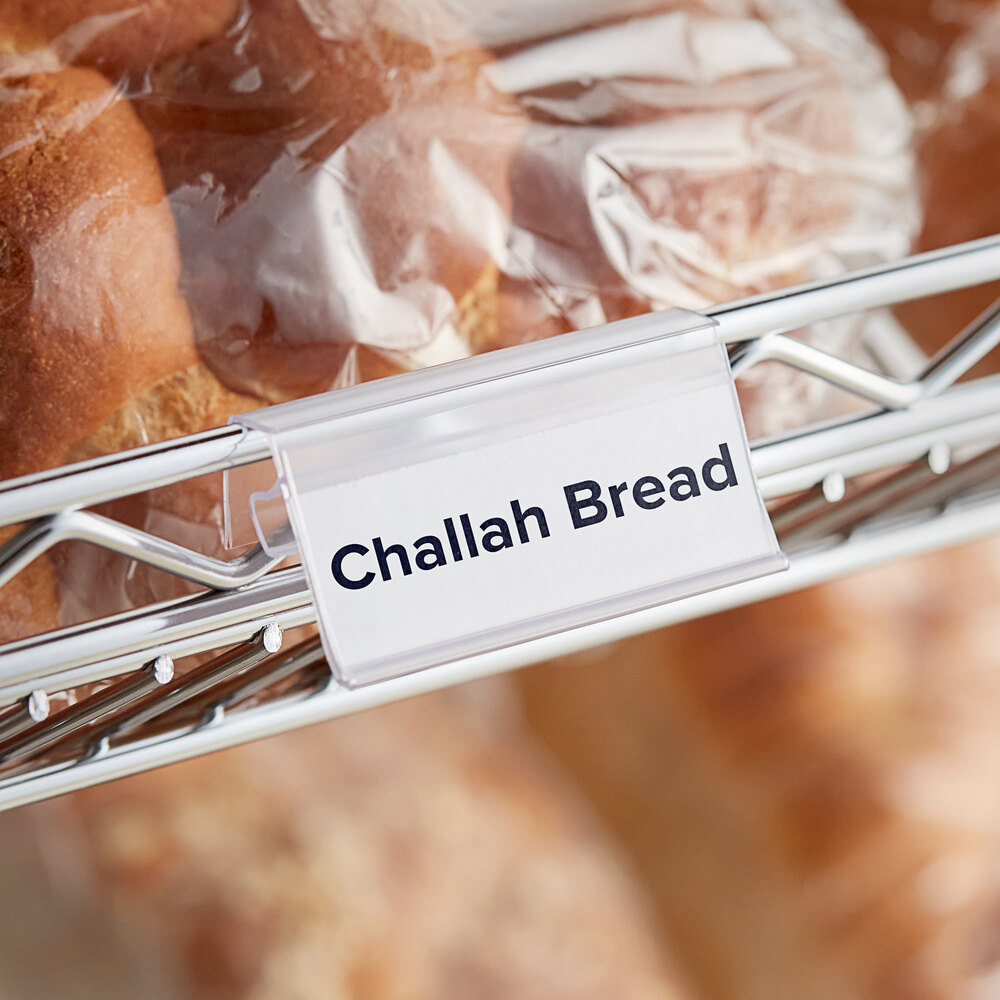 A clear clip-on label holder attached to wire basket shelving, displaying a label for challah bread.