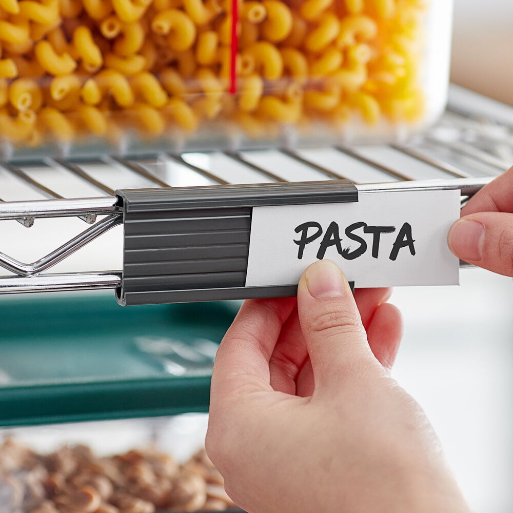 A gray label holder being attached to a wire shelving unit, with a label reading 'PASTA'.