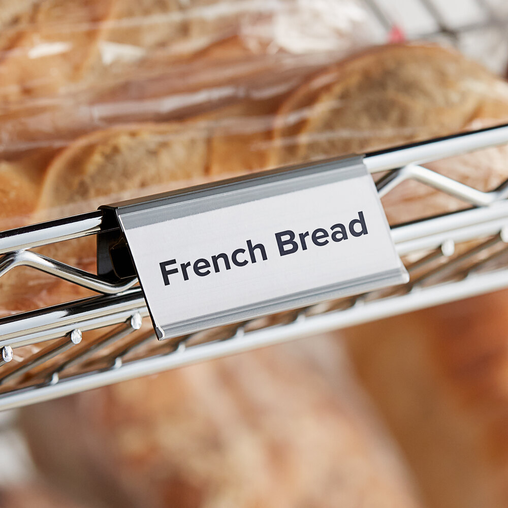 A gray clip-on label holder attached to wire basket shelving, displaying a label for French bread.