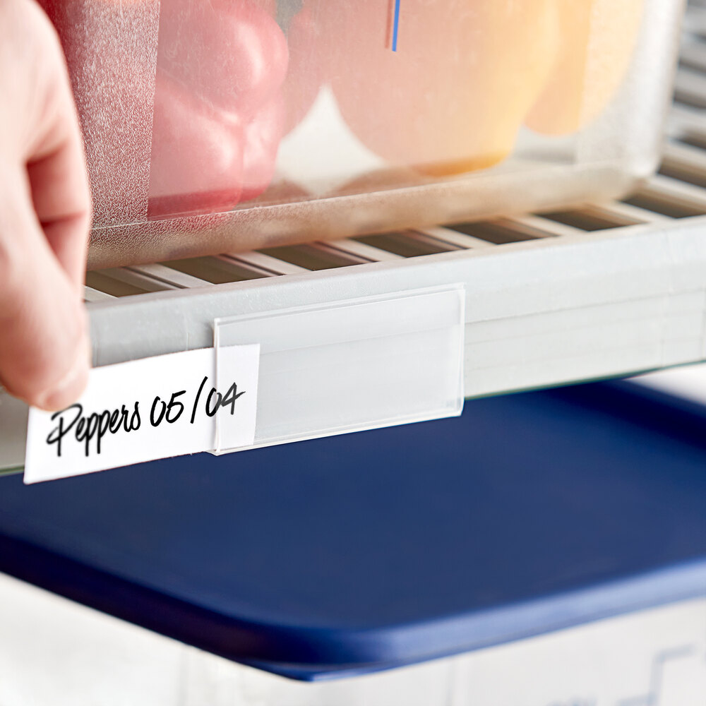 A clear clip-on label holder attached to a shelf, holding a handwritten label.