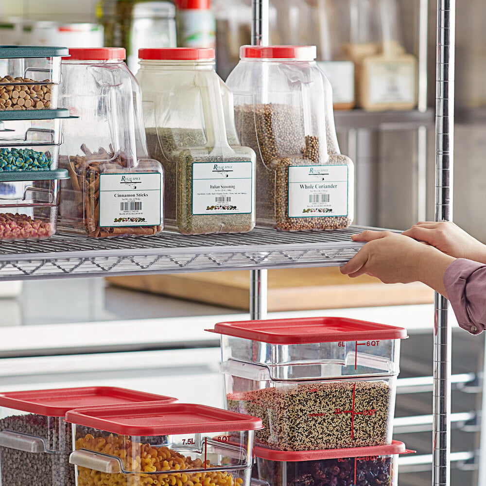 A person is organizing clear plastic containers with red lids and visible labels on a metal wire shelving unit in a kitchen or pantry setting.