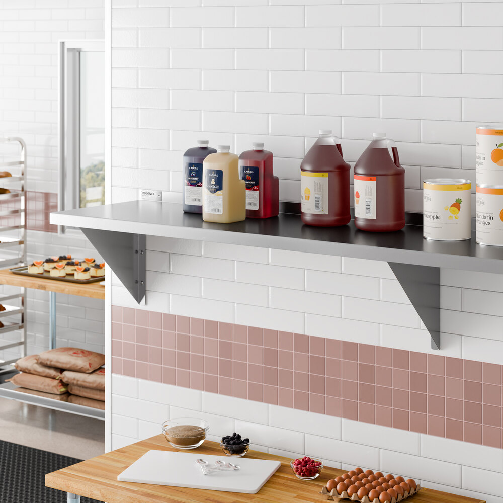 A stainless steel heavy duty wall shelf mounted on a tiled kitchen wall, holding various large containers and bottles.