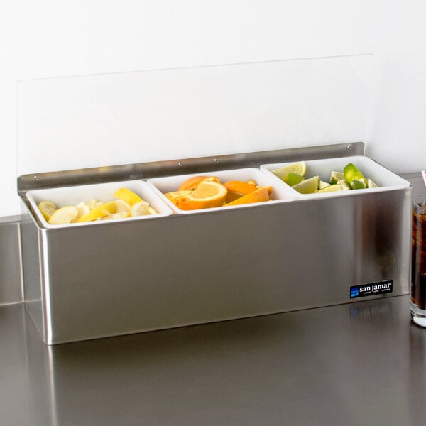 A San Jamar stainless steel condiment bar with fruit in containers.