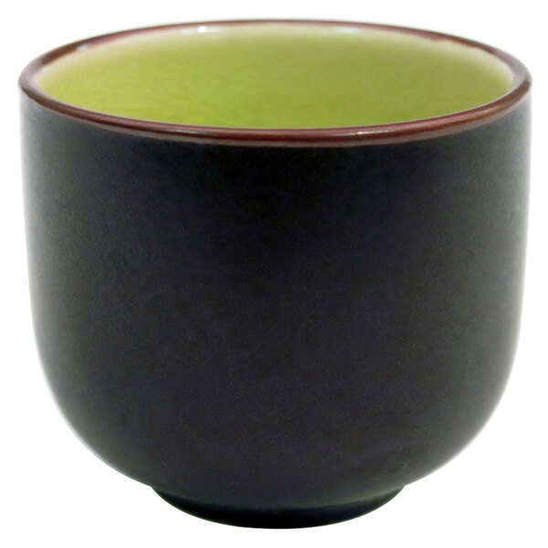 A black and green stoneware sake cup with a white border.