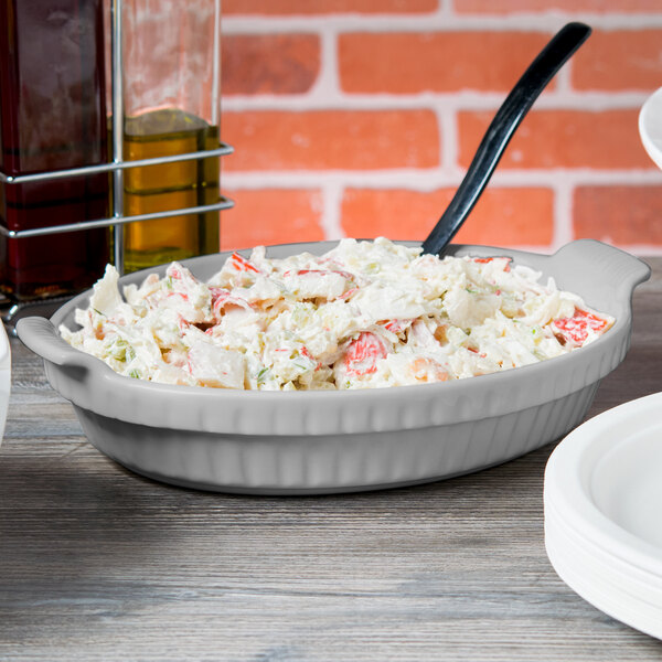 A white tablecraft shallow oval casserole dish filled with food.