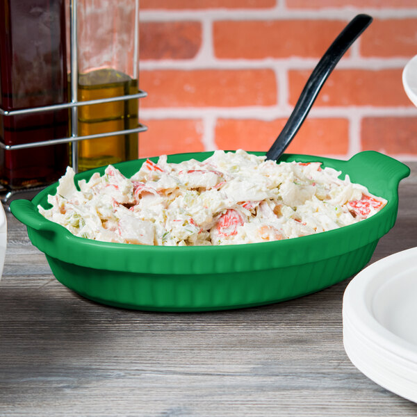 A green Tablecraft small shallow oval casserole dish with food on it.